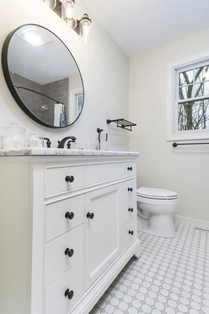 Bathroom remodel with a round mirror and white vanity