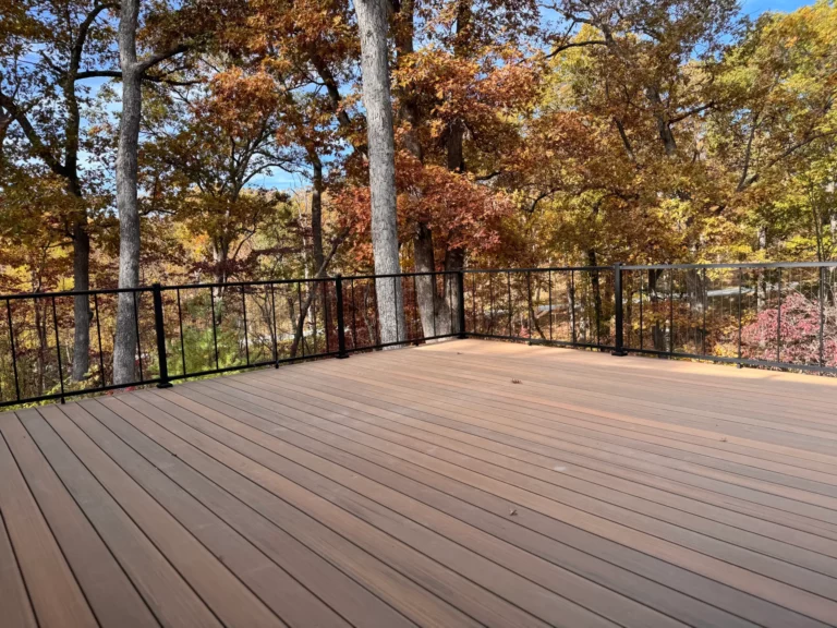 A wooden deck surrounded by vibrant autumn trees, featuring a clear blue sky in the background.